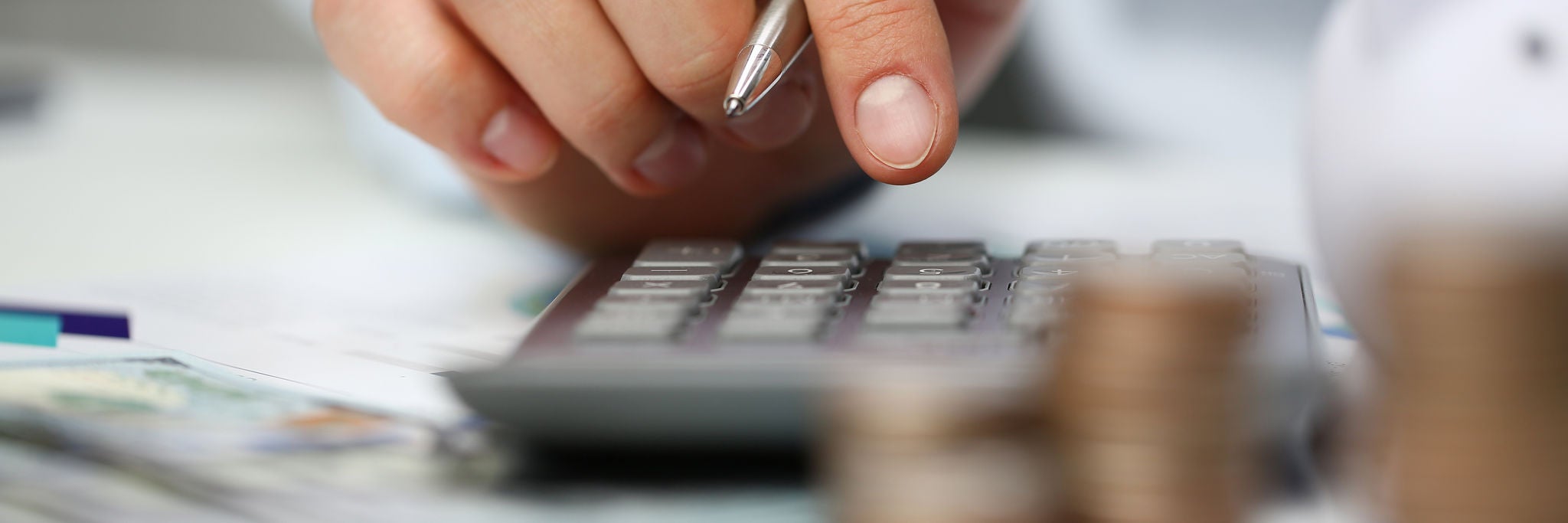 Male hand push key silver calculator is lying on desk cash dollar plots in home office setting. Calculation of family expenses social income population freelance irs situation growth research concept