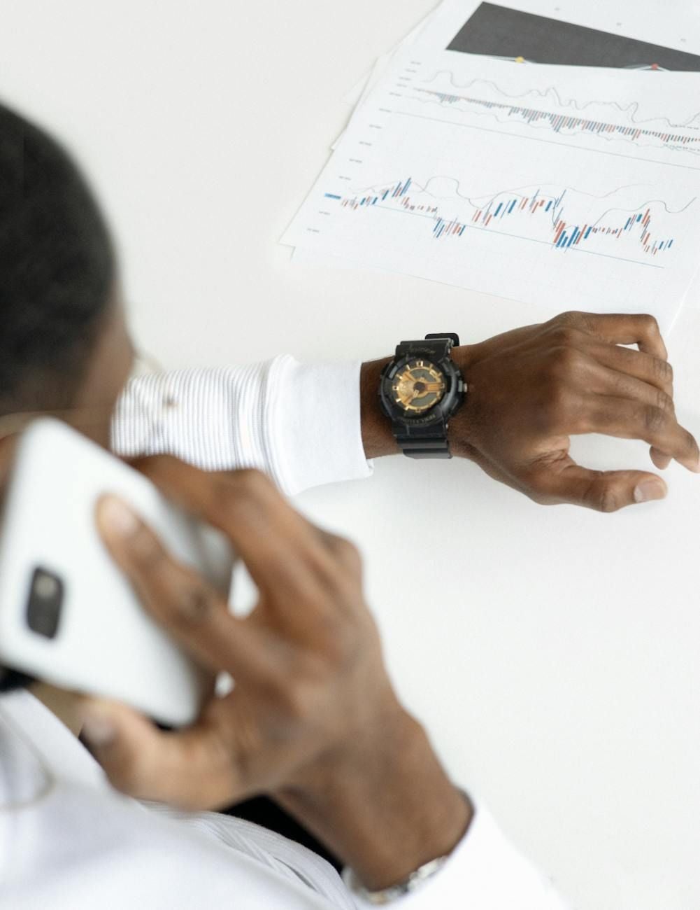 Man looking at his watch while talking on cell phone