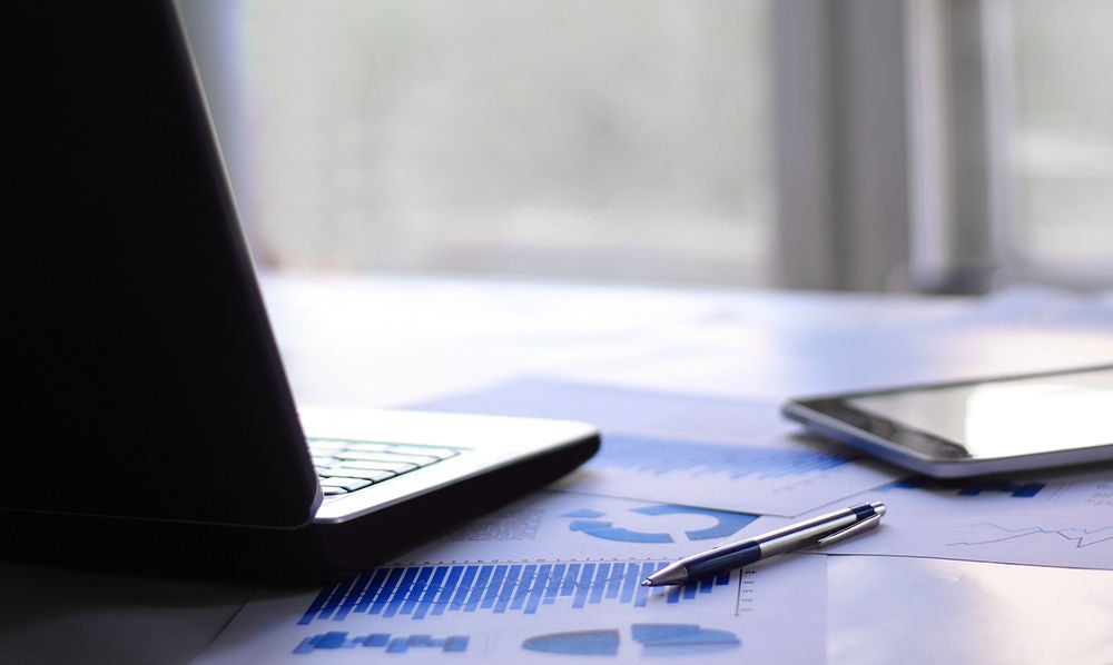 Business report, laptop and pen on a table