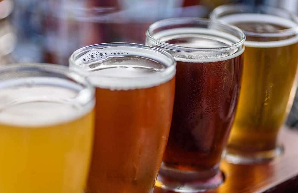 A line up of different shades of beers in pint glasses