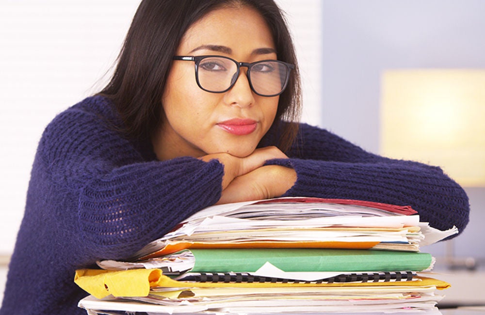 Woman wearing glasses leaning on a pile of papers