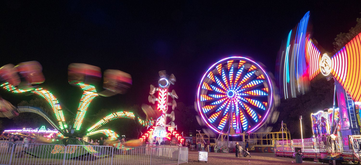 Lights from carnival rides blurry against a black night sky