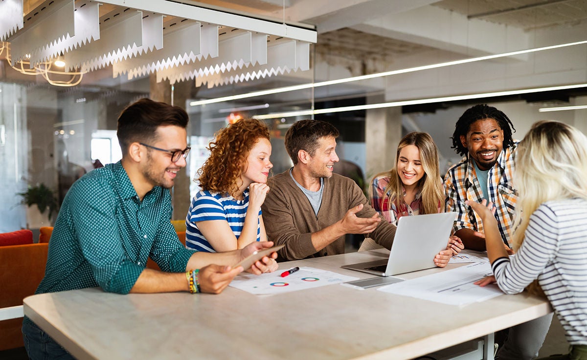 Group of business people crowded around a laptop at work in an office