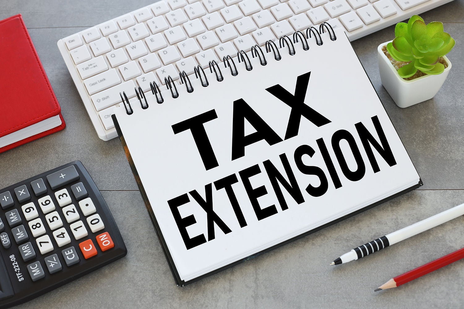 TAX EXTENSION text on an open notepad on a gray background.