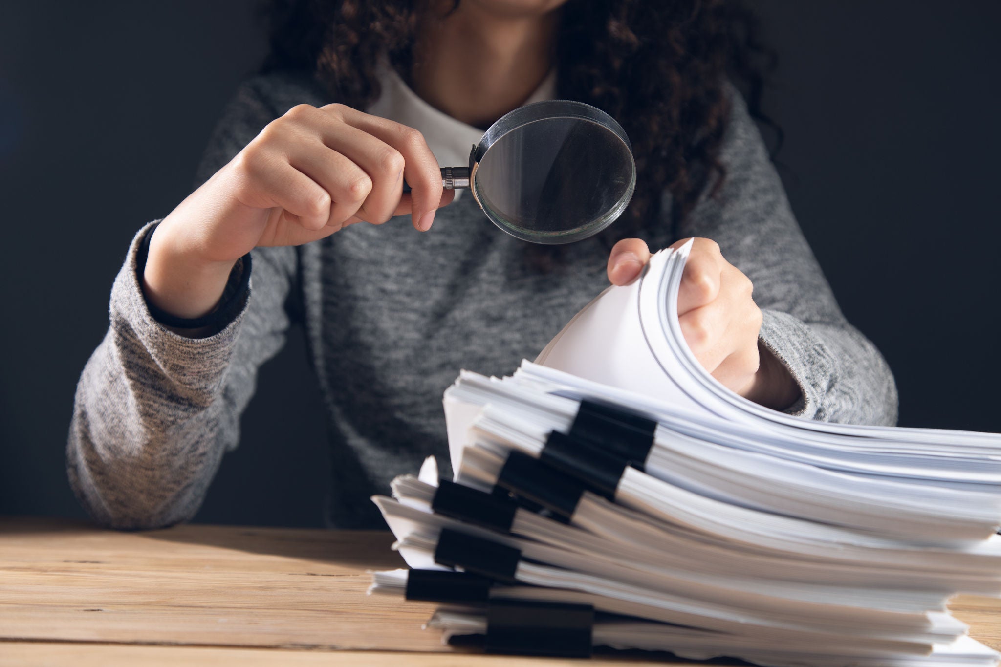 business woman holding magnifying glass and documents
