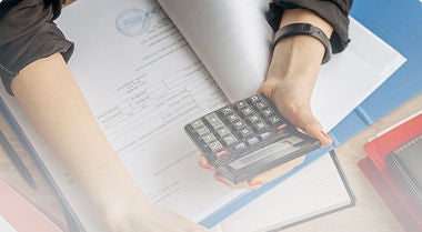 A person holding a calculator overtop some legal documents