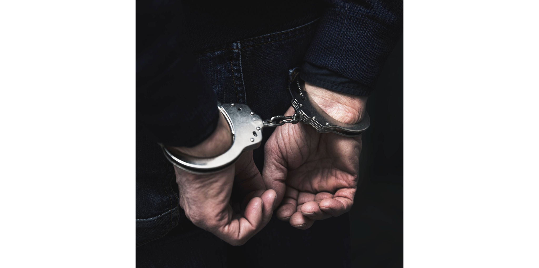 handcuffed arrested man behind prison bars. copy space