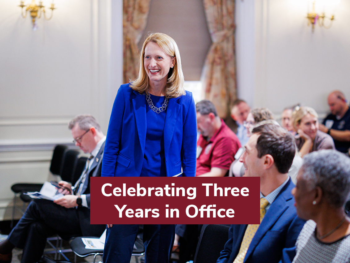 Brooke Lierman in the Comptroller's office assembly room, smiling and surrounded by guests.