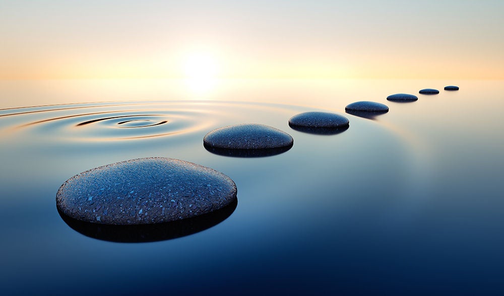 Line of stones in the water with the sun setting in the background
