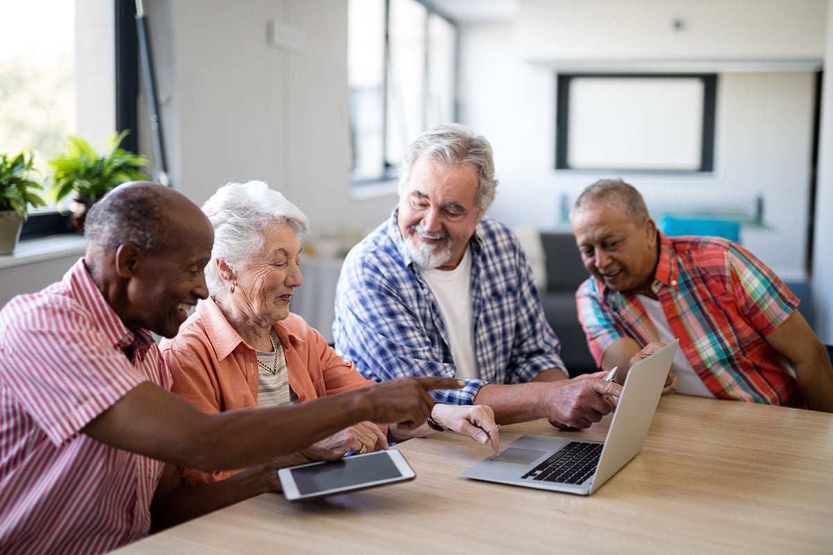 Happy mixed race senior men and woman using laptop
