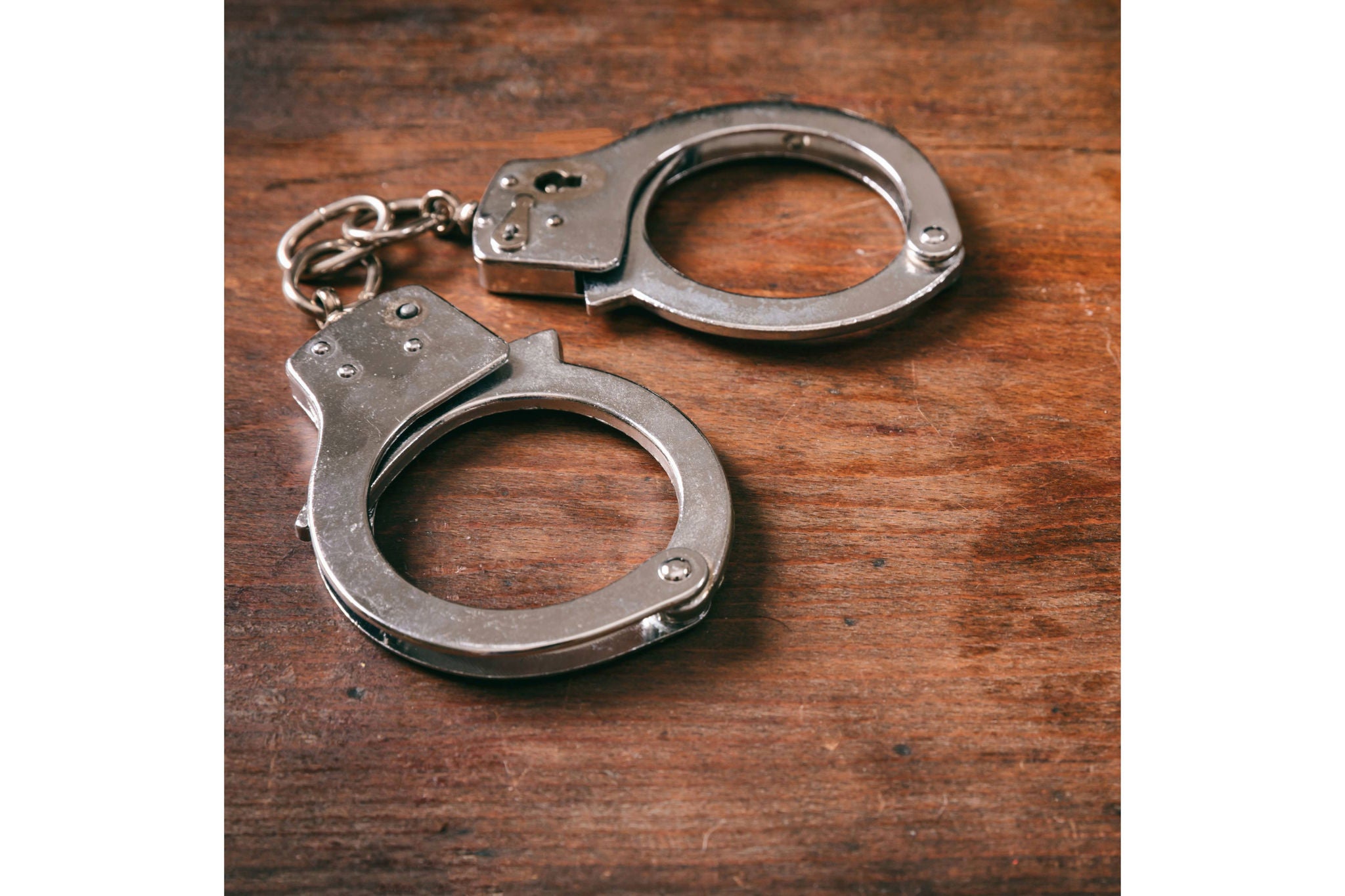 Law and order concept. Handcuffs isolated and copy space on a wooden background.