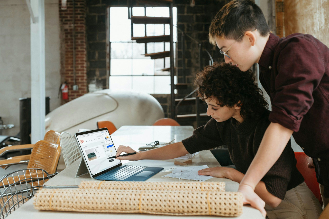 Two people standing over a laptop